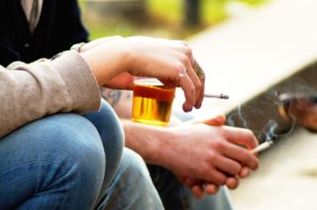 Hands holding alcohol and cigarettes