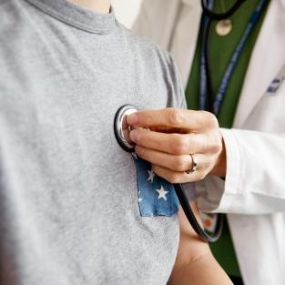 Doctor holding stethoscope on patient's chest