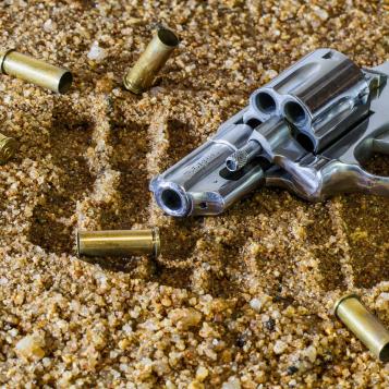Handgun and empty bullet casings on sand