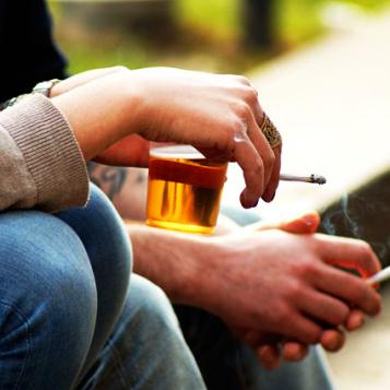 Hands holding alcohol and cigarettes