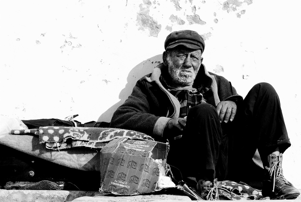 Homeless man sitting on street next to boxes