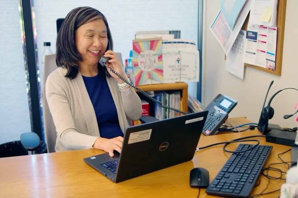 Person speaking on a telephone while seated in front of a laptop computer