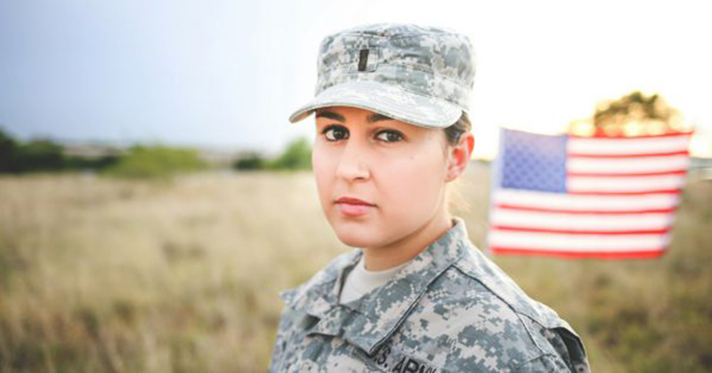 Veteran in a field standing front of a flag