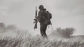 Black and white photo of a soldier standing in a field of tall grass