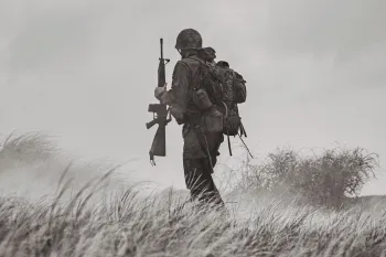 Black and white photo of a soldier standing in a field of tall grass