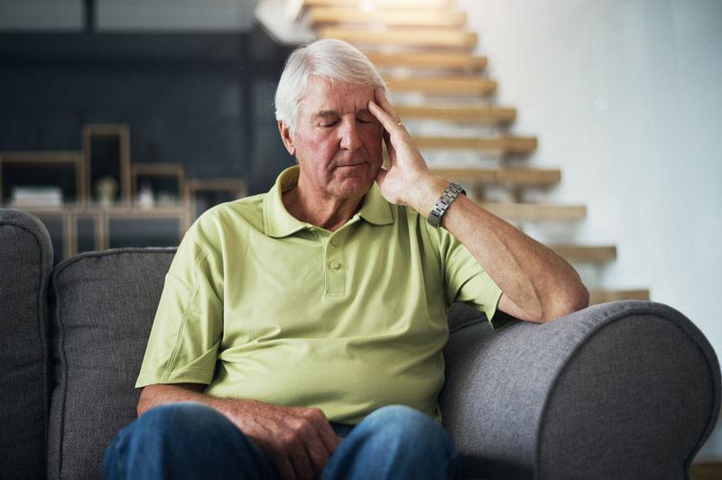 Sitting man with his eyes closed holding one hand up to the side of his head
