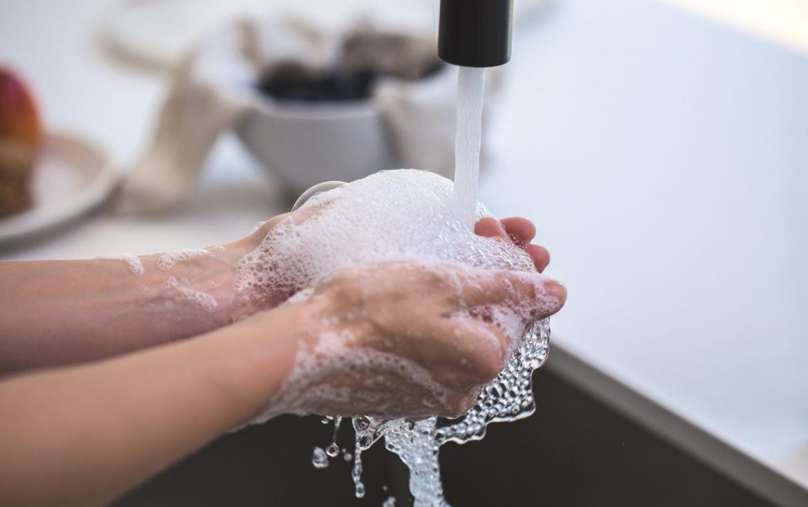Hands being washed with soap over a sink.