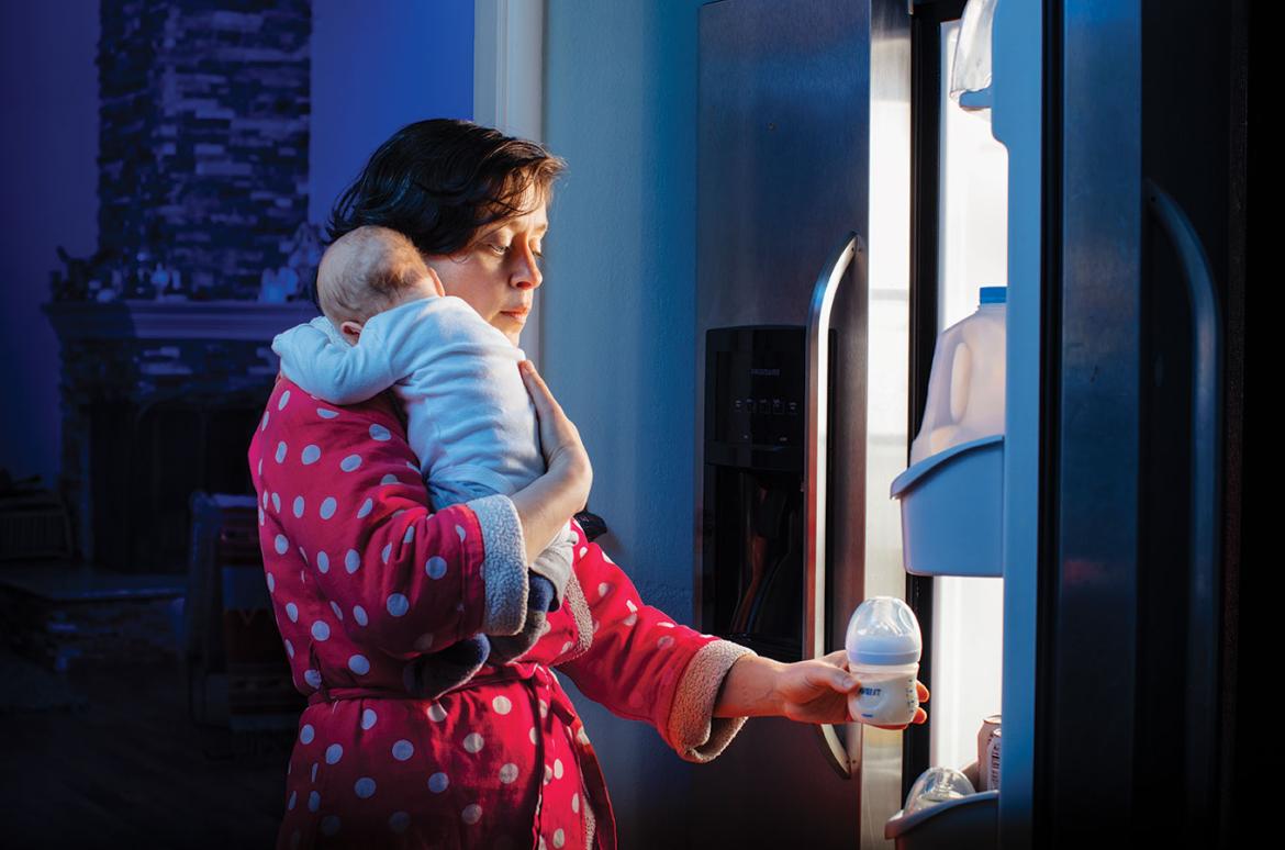 Person retrieving a bottle while holding an infant