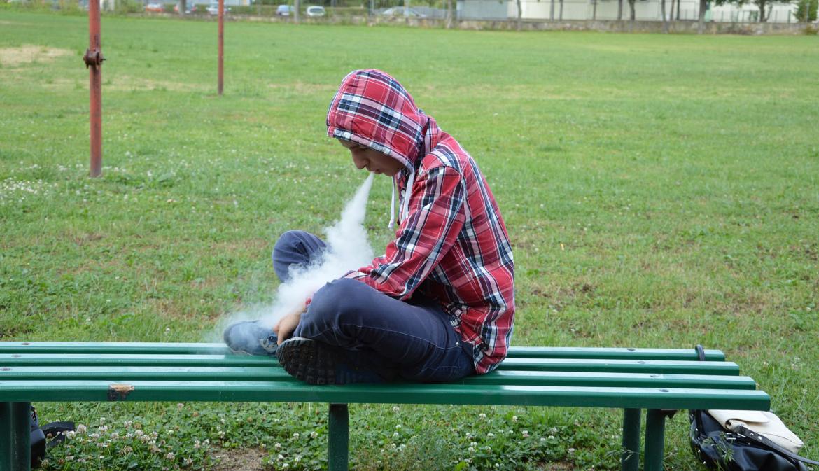 Teen vaping on bench