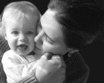 A baby daughter being kissed by her mother