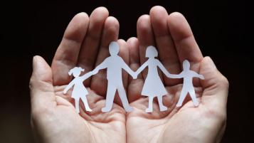 Hands holding a paper cutout family